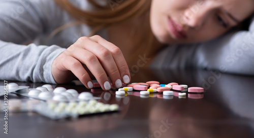 Emotional exhaustion and suicide. Closeup of depressed young lady with pills planning to kill herself, banner design