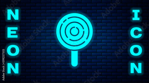 Glowing neon Lollipop icon isolated on brick wall background. Candy sign. Food, delicious symbol. Vector.