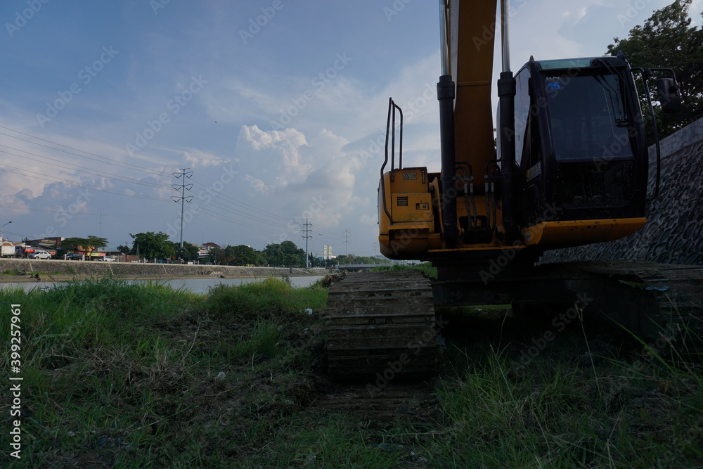Semarang, 15 October 2020; Yellow excavator that stopped at the river bank with a very beautiful blue sky.