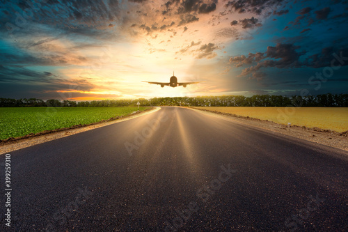 Asphalt road and sky flying airplane at sunset