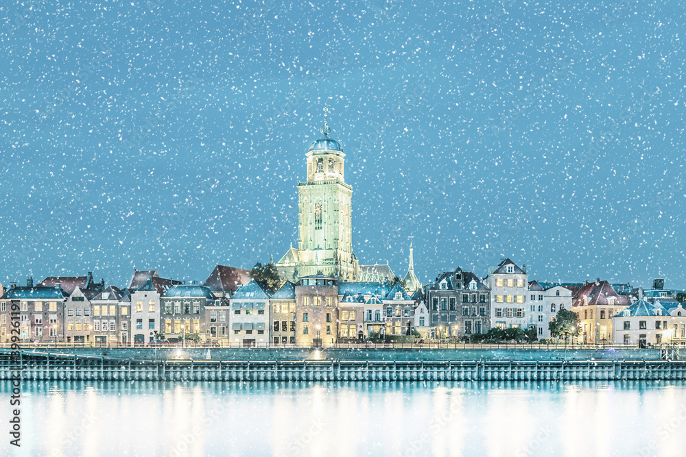 Winter view with snowfall of the Dutch city of Deventer in Overijssel with the river IJssel in front