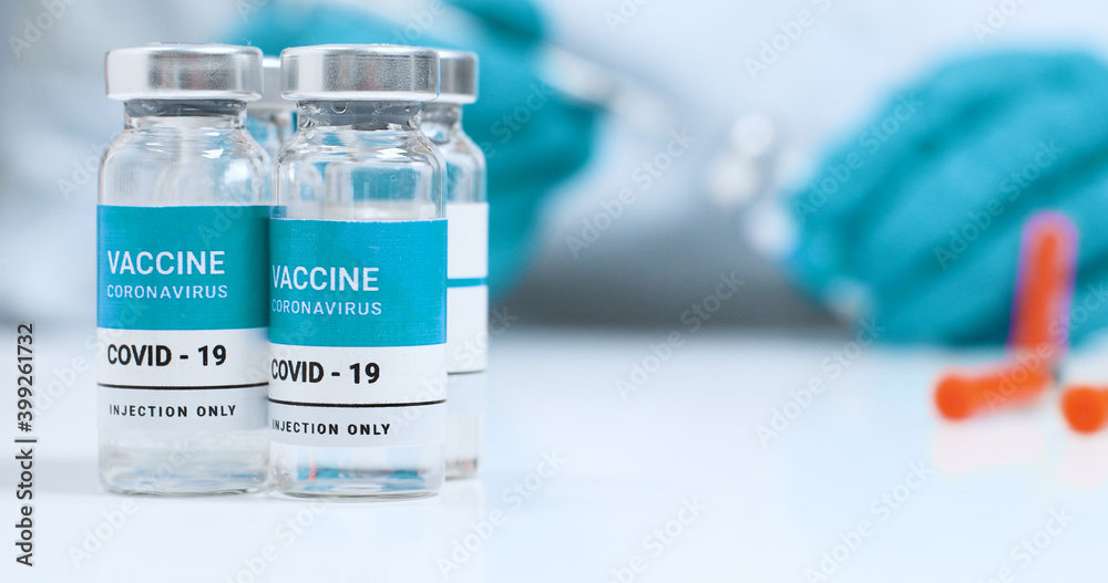 Corona virus, Sars-Cov-2 vaccine concept. Doctor hands in blue medical gloves with transparent liquid coronavirus vaccine bottle and syringe for injection in the laboratory. Corona virus, Sars-Cov-2 vaccine concept. Doctor hands in blue medical gloves with transparent liquid coronavirus vaccine bottle and syringe for injection in the laboratory.