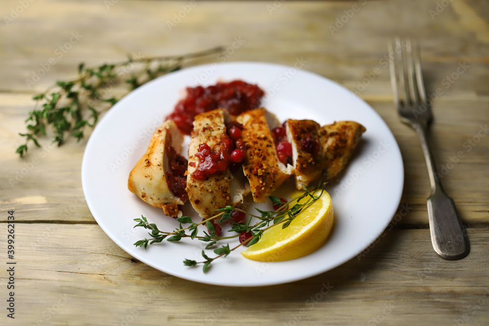 Juicy turkey fillet in slices with cranberry sauce on a plate. Festive food. Juicy turkey fillet in slices with cranberry sauce on a plate. Festive food.