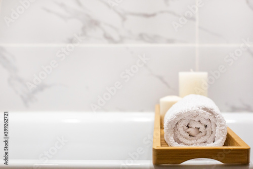 Close up view of marble white bathroom accessories, white towels, candles and copy space