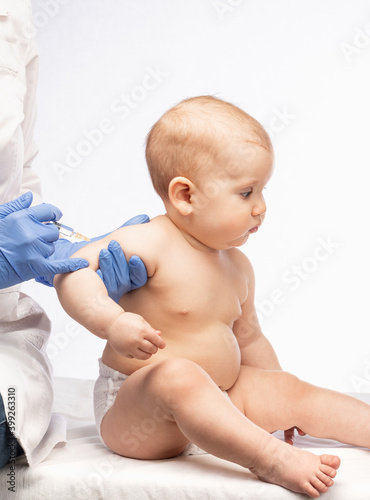 Doctor injecting a vaccine in arm of baby girl photo