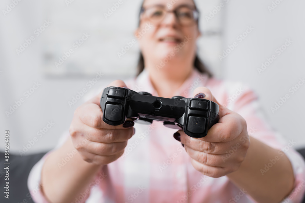 KYIV, UKRAINE - DECEMBER 07, 2020: Black joystick in hands of blurred plus size hispanic woman on background
