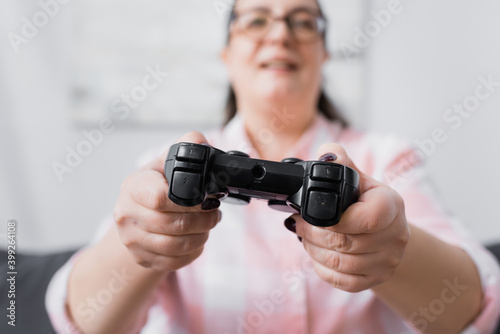 KYIV, UKRAINE - DECEMBER 07, 2020: Black joystick in hands of blurred plus size hispanic woman on background © LIGHTFIELD STUDIOS