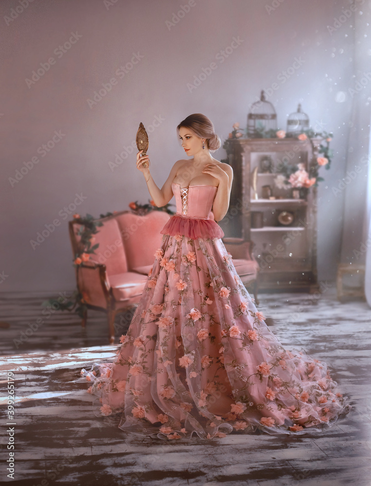 beautiful woman in sexy long medieval pink dress, spring flowers on skirt,  looks at herself. Holds