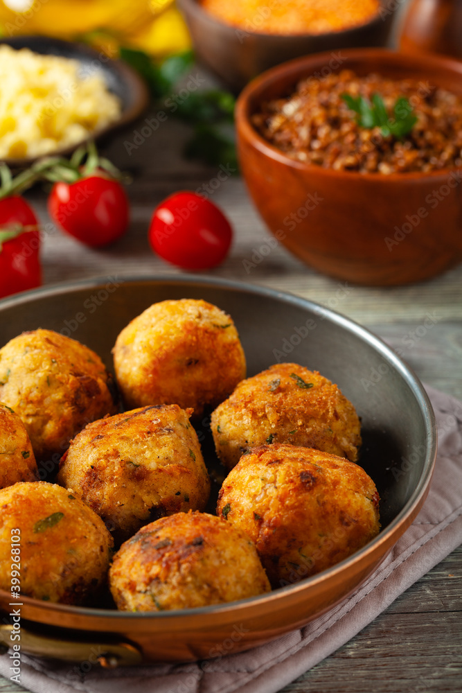 Lentil and millet meatballs. Served on tomato salsa with buckwheat. Gray plate, wooden boards in the background. Front view.