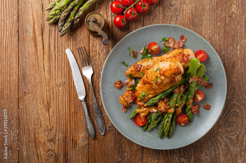 Roasted chicken breast, served on asparagus with tomato sauce, dried tomatoes. Top view.