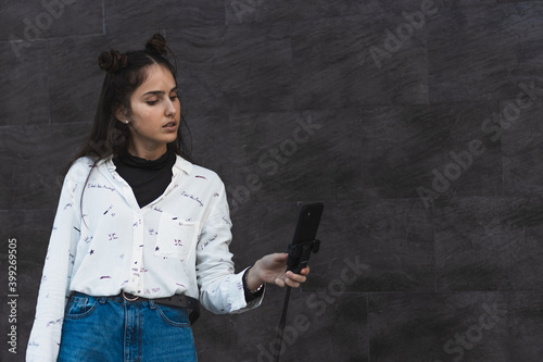 girl creating videos, with tripod and mobile phone in hand, filming with the camera