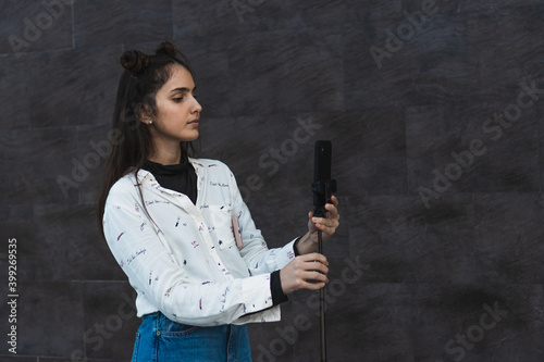 girl creating videos, with tripod and mobile phone in hand, filming with the camera
