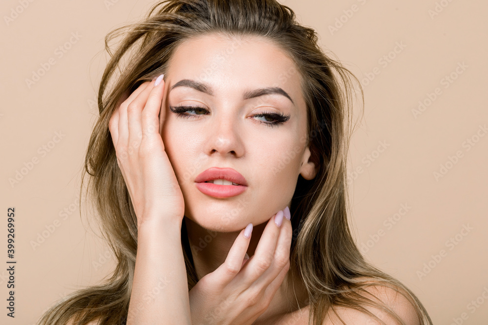 Beautiful woman face portrait. Beauty skin care concept. Sensual pretty young blond Caucasian woman with natural makeup, touching her face and looking away, isolated on beige background Beautiful woman face portrait. Beauty skin care concept. Sensual pretty young blond Caucasian woman with natural makeup, touching her face and looking away, isolated on beige background