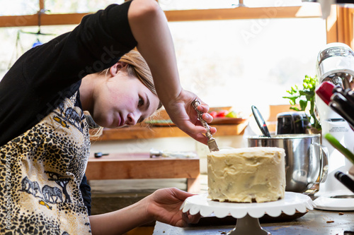 Teenage girl in kitchen applying icing to cake  photo