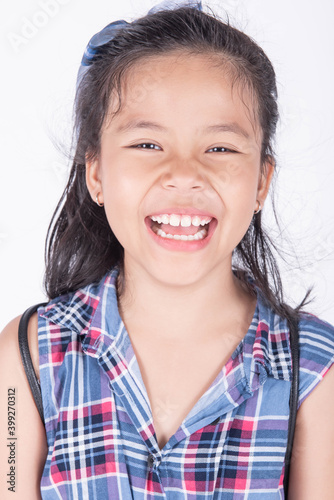 Portrait of cute casual smiling asian girl 8-9 year old posing and looking at camera isolated on light background. Laughing people. Positive emotions. Childhood concept.