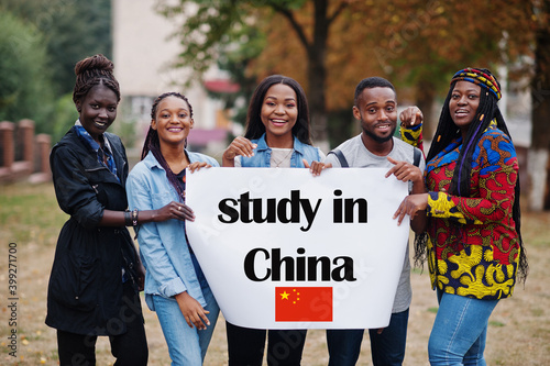 Study in China. Group of five african college students on campus at university yard hold white blank. Abroad countries for student concept.