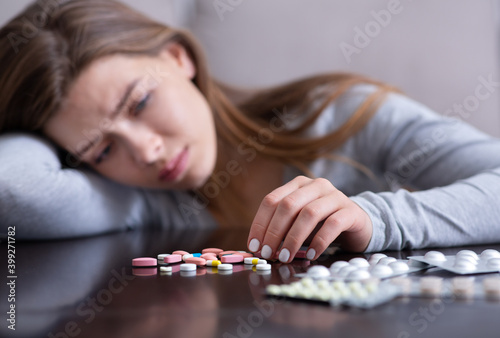 Young woman with pile of antidepressants planning to kill herself, committing suicide, suffering from mental distress