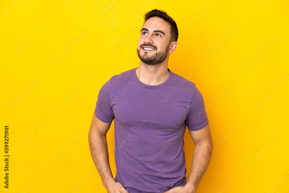 Young caucasian handsome man isolated on yellow background thinking an idea while looking up Young caucasian handsome man isolated on yellow background thinking an idea while looking up