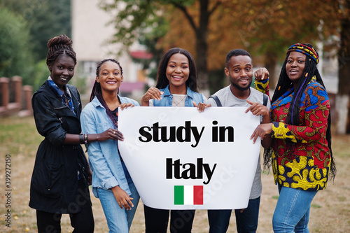 Study in Italy. Group of five african college students on campus at university yard hold white blank. Abroad countries for student concept.