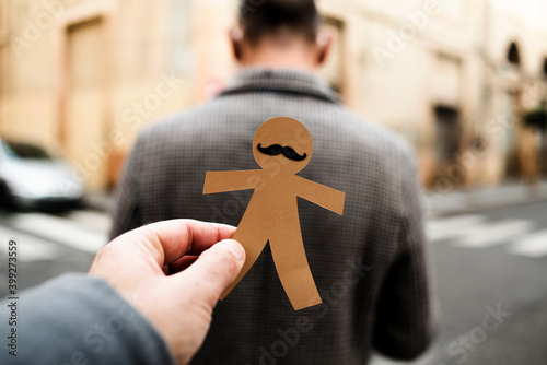 man about to stick a paper man doll to another man photo