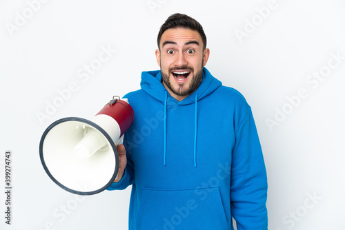 Young caucasian handsome man isolated on white background holding a megaphone and with surprise expression