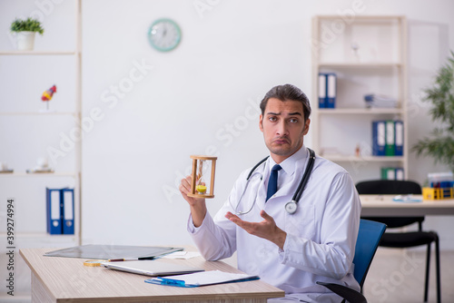 Young male doctor in time management concept