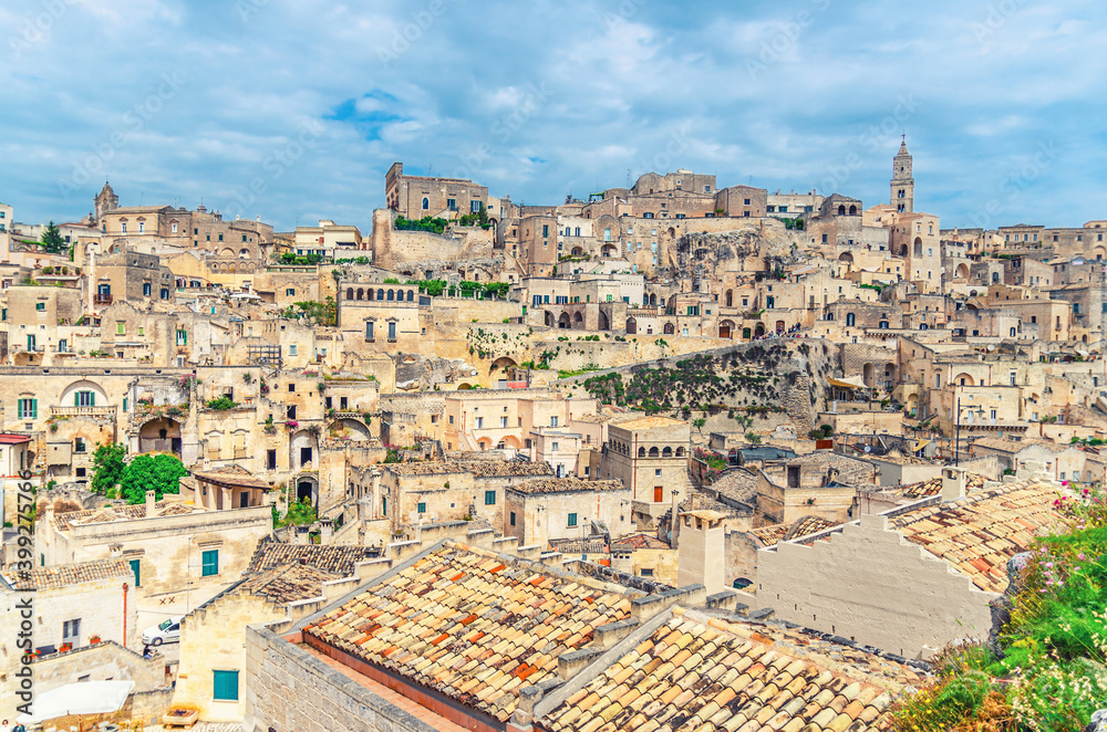 Sassi di Matera old ancient town, aerial panoramic view of historical centre Sasso Caveoso with rock cave houses, blue sky and white clouds, UNESCO World Heritage, Basilicata, Southern Italy