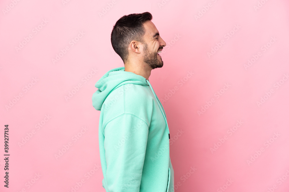 Young caucasian handsome man isolated on pink background laughing in lateral position Young caucasian handsome man isolated on pink background laughing in lateral position