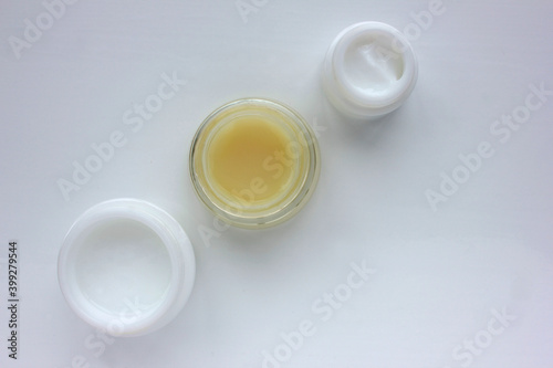 Facial cream on white background. Flat lay composition with variety of face cream in glass jars. Copy space