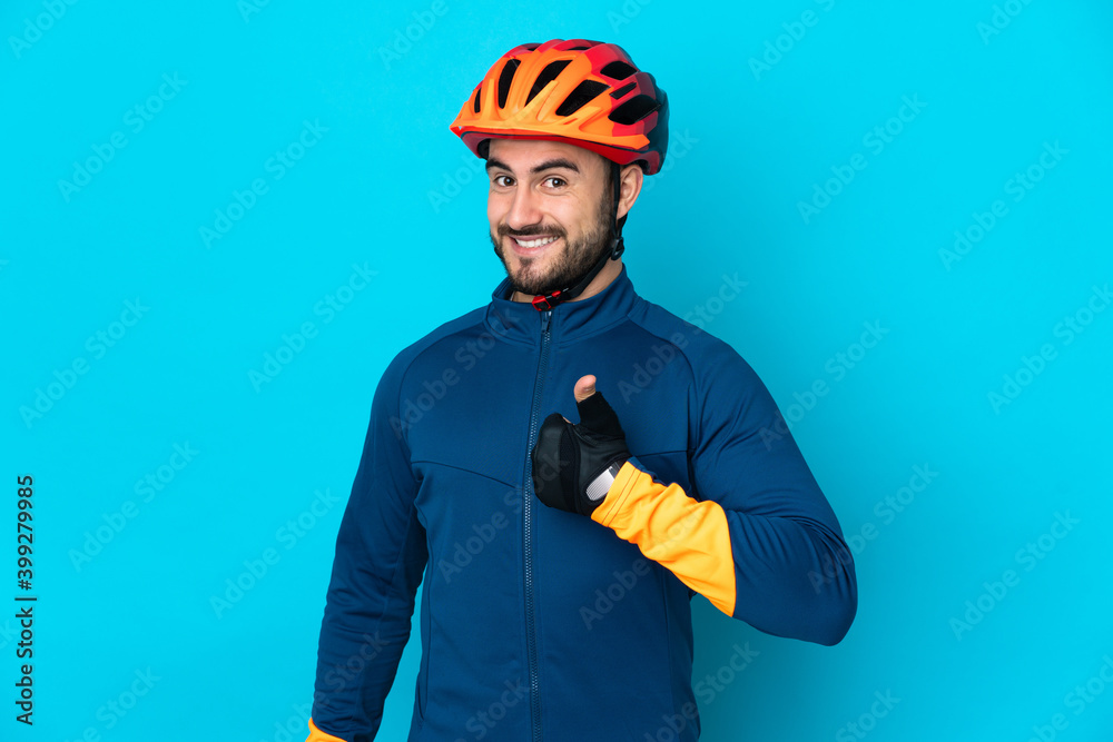 Young cyclist man isolated on blue background giving a thumbs up gesture