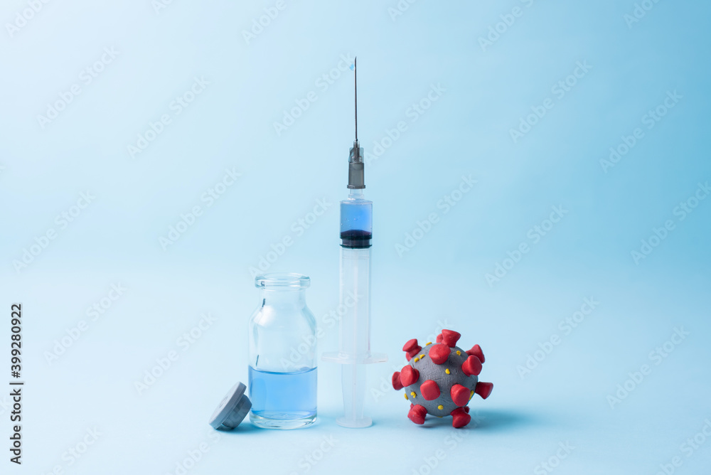 Coronavirus model, a syringe with vaccine and vaccine bottle on blue background. Coronavirus model, a syringe with vaccine and vaccine bottle on blue background.