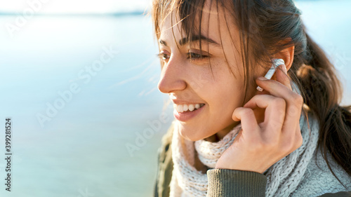 close up potrait becalmed woman listening to music in wireless earphones during walk alone photo