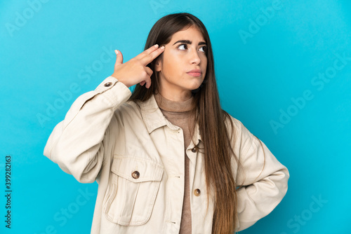 Young caucasian woman isolated on blue background having doubts