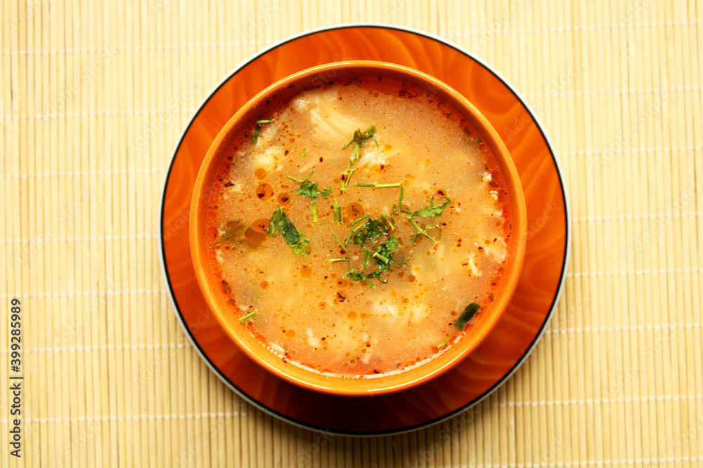 Bowl of chicken soup with spice, top view, bamboo table background