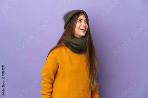 Young caucasian girl with winter hat isolated on purple background laughing © luismolinero