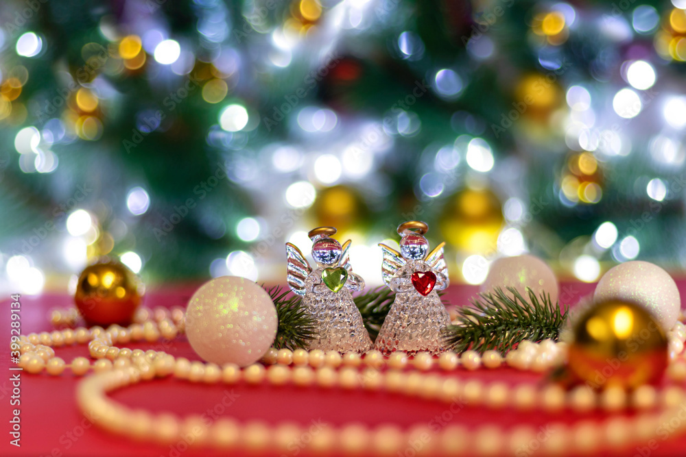 Two angels with blur white Christmas balls and Christmas beads on bokeh background. Christmas background or Christmas card. New Year or Xmas concept. Copy space.