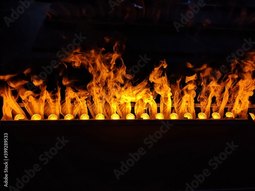 Closeup of electric artificial fireplace with orange fire flame