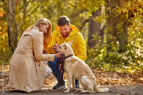 couple dressed casual hugging and taking a walk in nature with their lovely nice dog , autumn season © alfa27