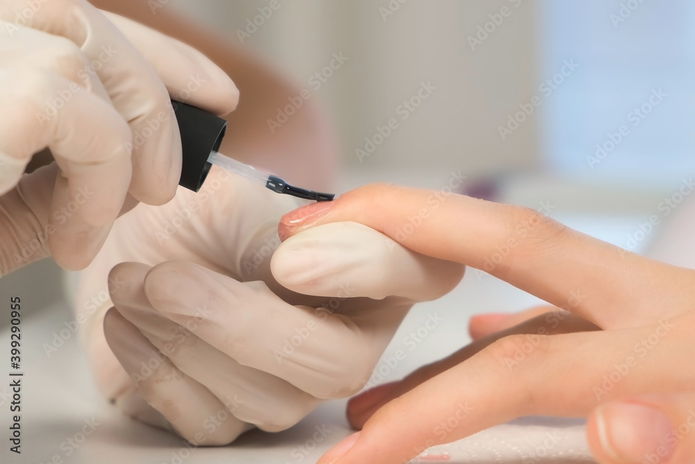 Woman manicurist master in gloves is applying top coat on pink gel on client's nails in beauty salon, hands closeup. Manicure nail paint. Nail polish. Hygiene care about nails. Beauty procedure. Woman manicurist master in gloves is applying top coat on pink gel on client's nails in beauty salon, hands closeup. Manicure nail paint. Nail polish. Hygiene care about nails. Beauty procedure.