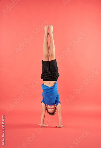 Vászonkép Adorable male child in sportswear doing handstand exercise