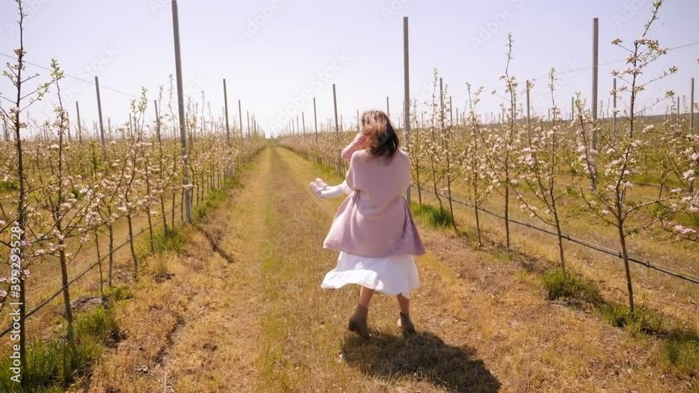 Happy mother and daughter are having fun on the background of a green blooming apple orchard, the mother is circling her daughter in her arms. Happy mother and daughter are having fun on the background of a green blooming apple orchard, the mother is circling her daughter in her arms.