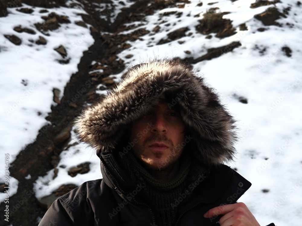 guy in a cold day, with snow behind. Wearing a hood guy in a cold day, with snow behind. Wearing a hood