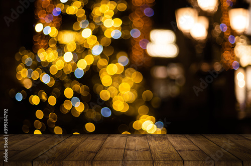 Old weathered wooden board or rustic table top with a sparkling bokeh of golden party lights in the background photo