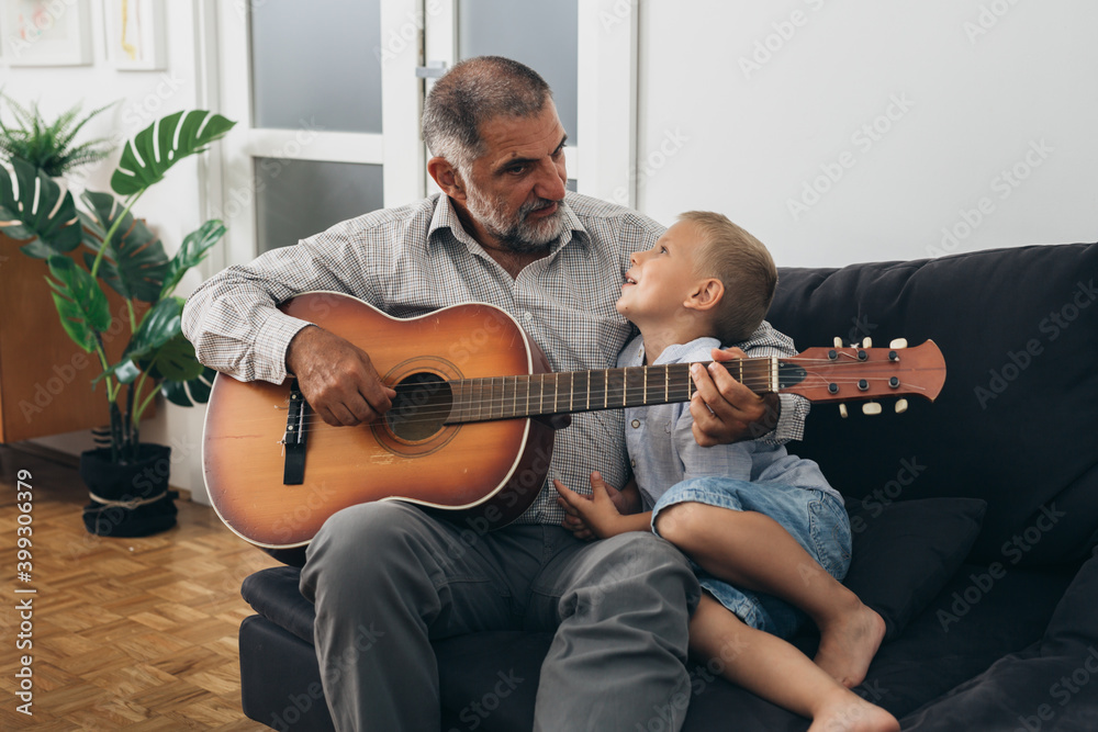 Obraz premium boy with his grandfather playing guitar at home