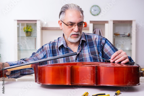 Obraz na plátně Senior male repairman repairing musical instruments at home