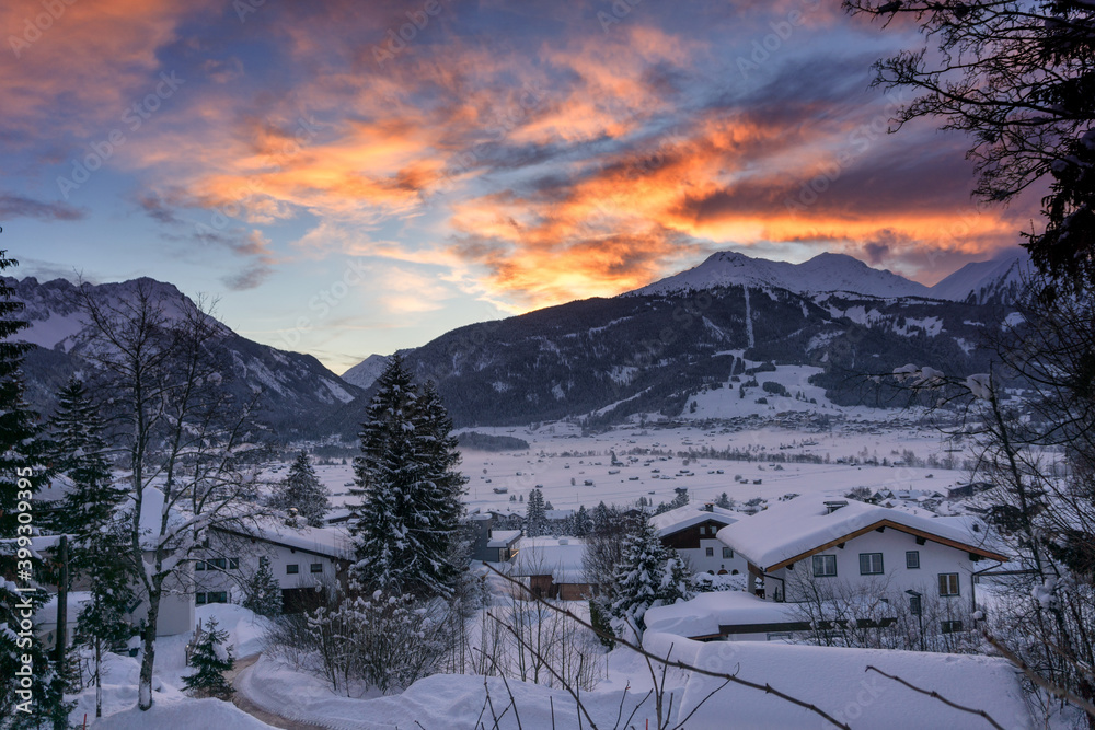 Sunset over the mountains. Winter mountain landscape. Dark blue sky with dramatic coluds. Ehrwald, Austria, Europe.