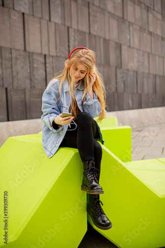 Photography Young woman listen to the music from mobile phone on modern public bench