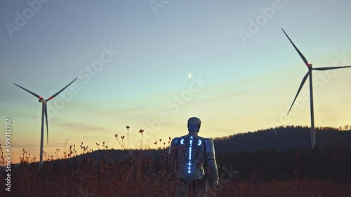 Future droid cybernetic prototype worker walking on agricultural wind station with eco-friendly windmill turning generating sustainable energy. Cyborg. AI concept.