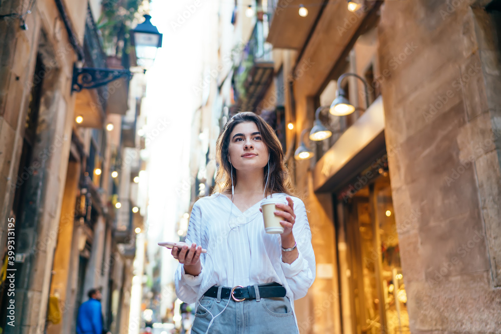 Positive woman listening to music and drinking coffee