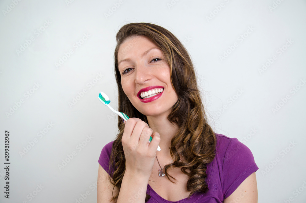 Brunette young woman with amazing white teeth holding tooth brush, studio shot , gray background Brunette young woman with amazing white teeth holding tooth brush, studio shot , gray background